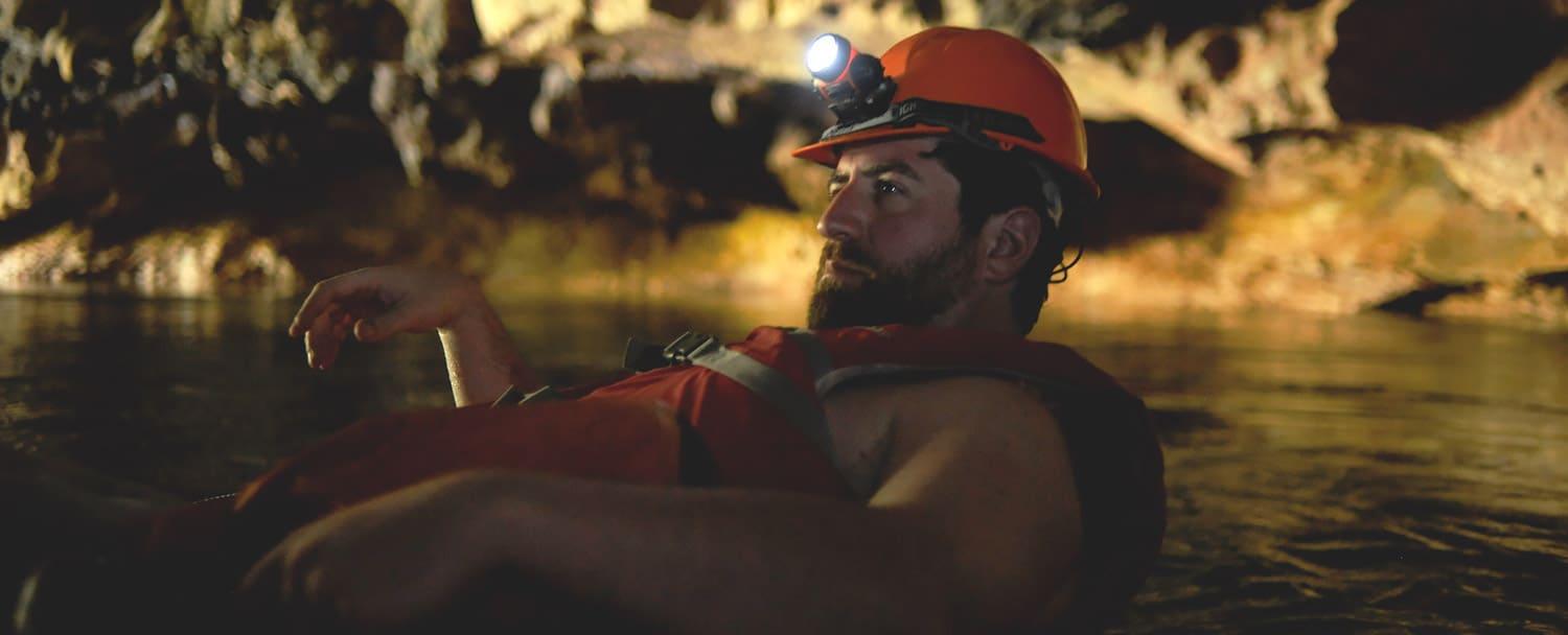 man cavetubing in belize with headlamp and innertube