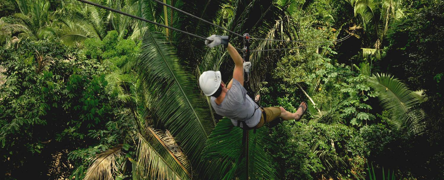 Man ziplining in Belize through jungle canopy