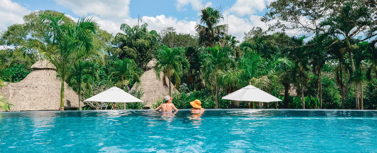 couple lounging at chaa creek infinity swimming pool